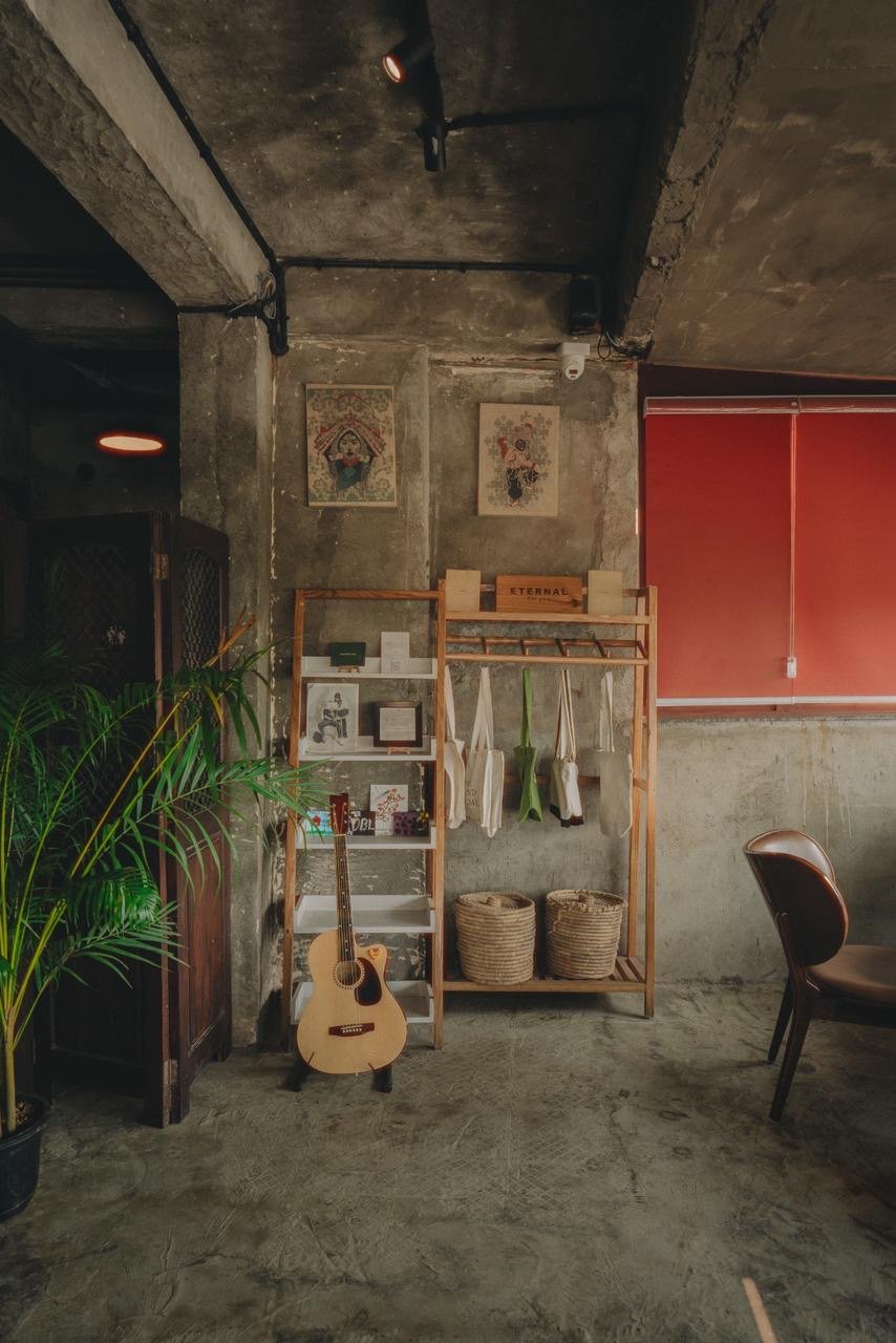 A guitar, woven baskets and framed Tibetan art in a concrete-walled corner of the café