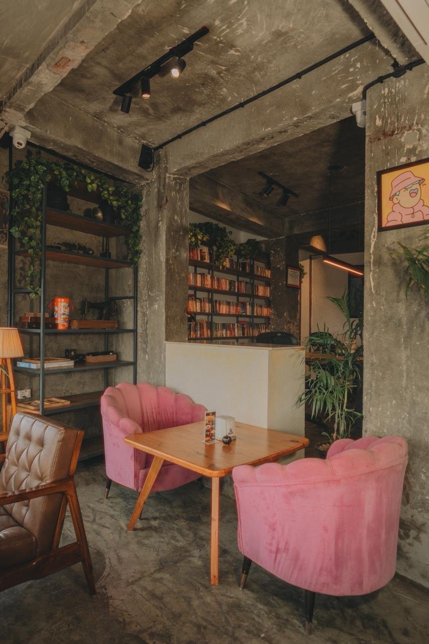 Two pink velvet armchairs by bookshelves