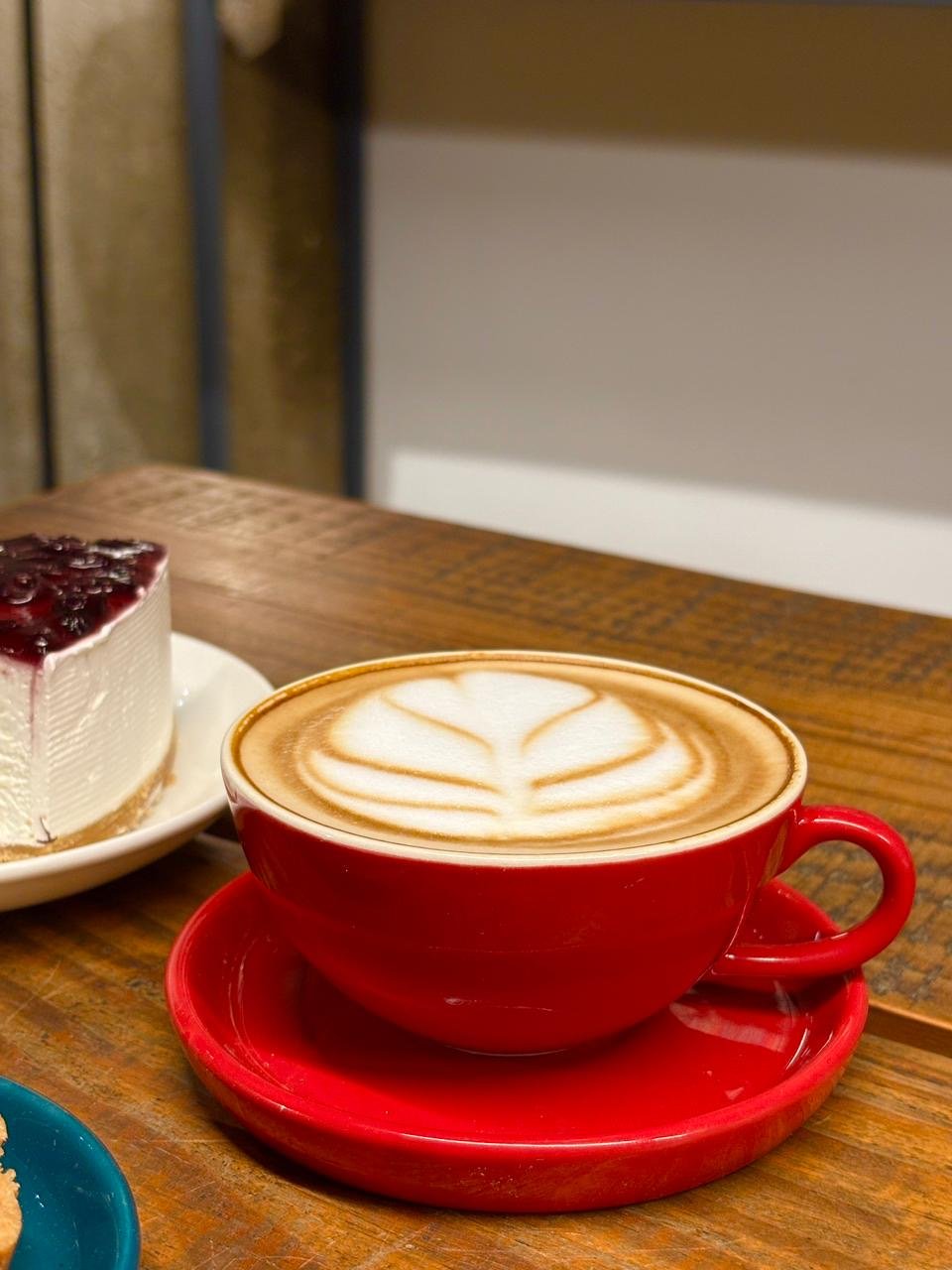 Latte art in a red cup on a wooden table